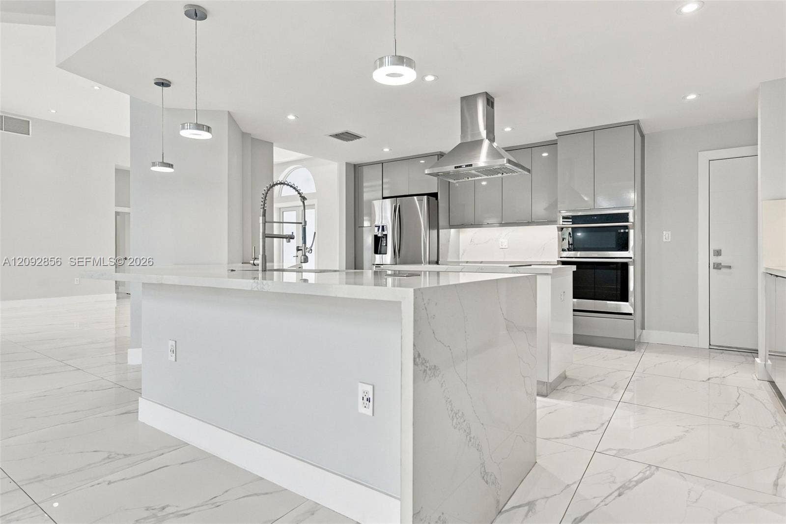 18919 SW 24th Street, #18919, Miramar, Miramar, FL 33029 Kitchen featuring a stone-surface waterfall island, high-gloss cabinetry, stainless steel wall-mounted oven and microwave, stainless steel range hood, and large-format tile flooring