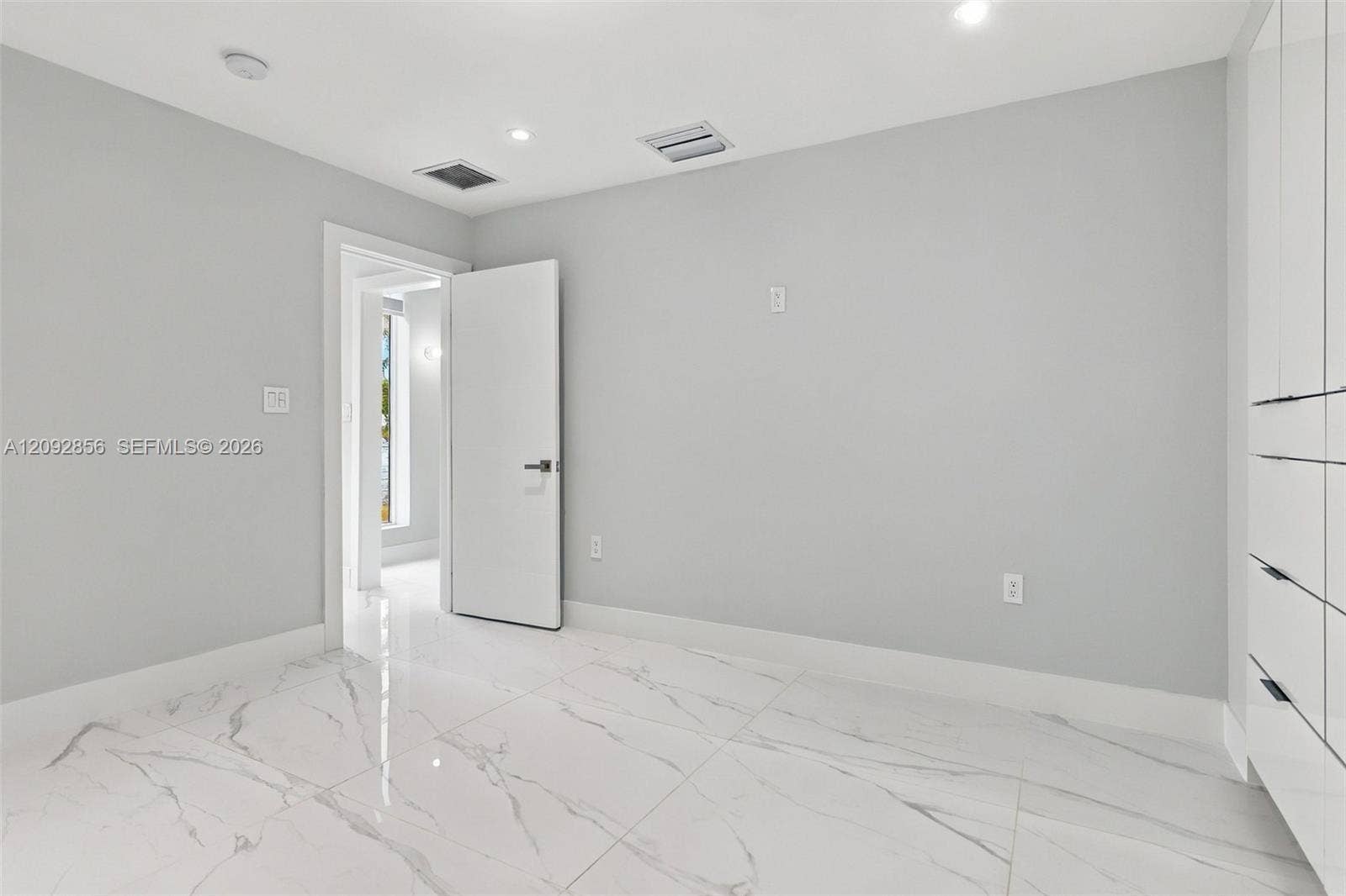 18919 SW 24th Street, #18919, Miramar, Miramar, FL 33029 2nd bedroom - 1st floor - Neutral-toned room featuring large-format stone-patterned tile flooring, recessed ceiling lighting, and floor-to-ceiling built-in cabinetry with integrated hardware