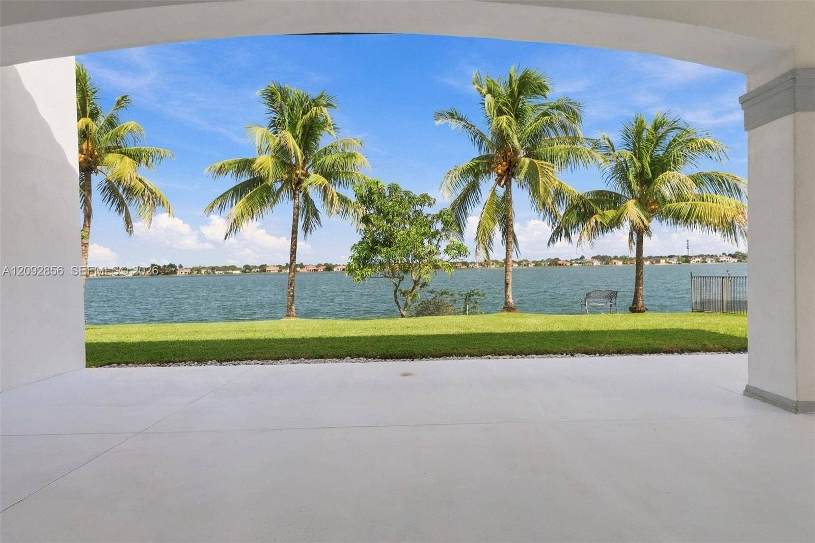 18919 SW 24th Street, #18919, Miramar, Miramar, FL 33029 Covered patio featuring a concrete floor, arched structural support, manicured lawn, palm trees, and water frontage