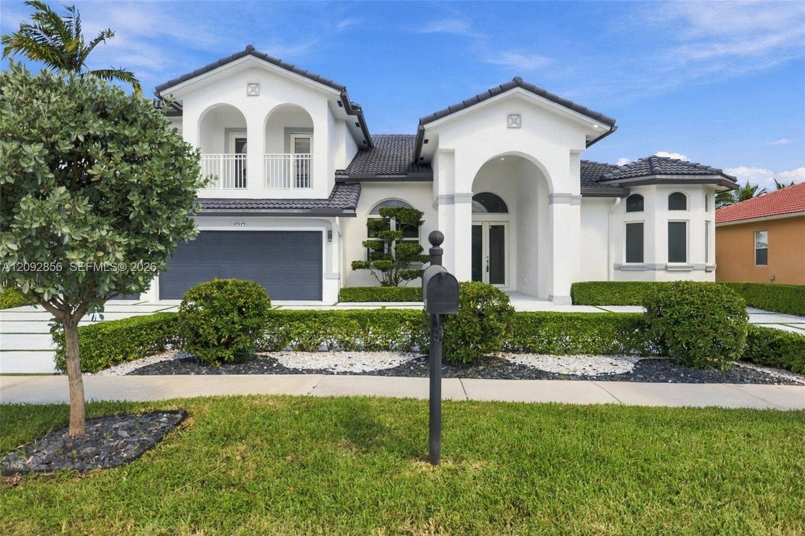 18919 SW 24th Street, #18919, Miramar, Miramar, FL 33029 Two-story residence featuring a tile roof, arched entryway, upper-level balcony, and a multi-car garage with a concrete paver driveway