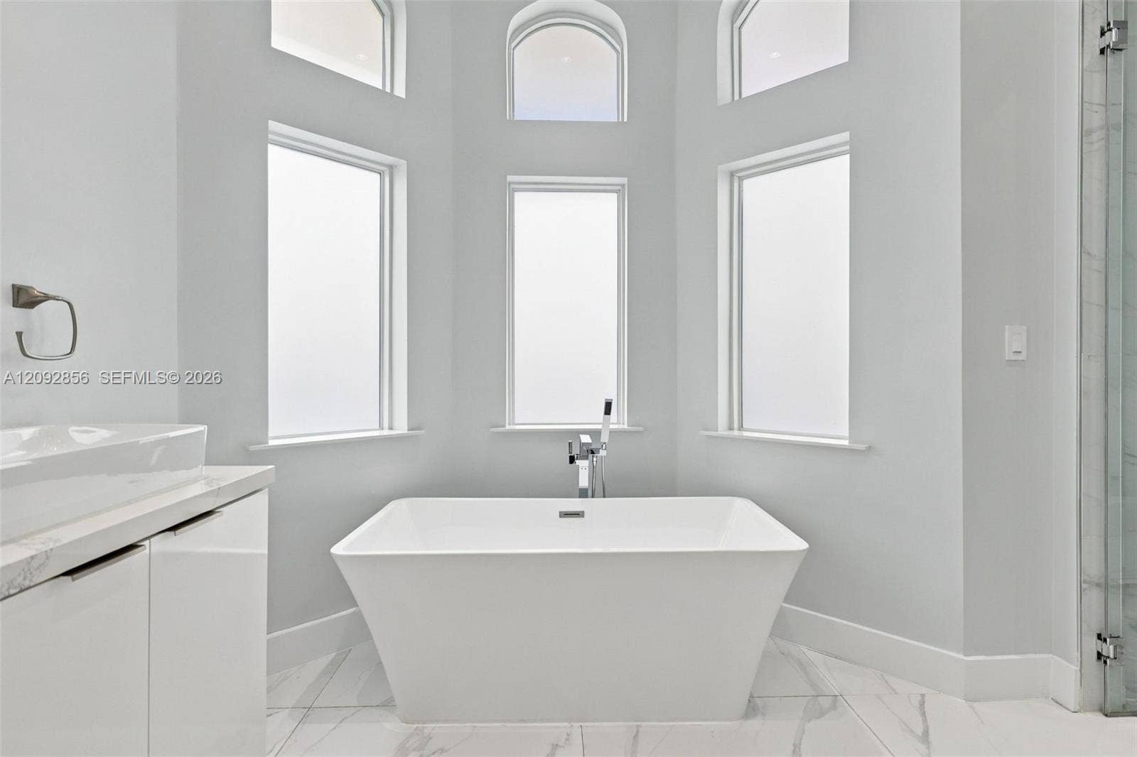 18919 SW 24th Street, #18919, Miramar, Miramar, FL 33029 Freestanding rectangular soaking tub with a deck-mounted faucet, set against a wall of three tall windows topped by three arched transom windows