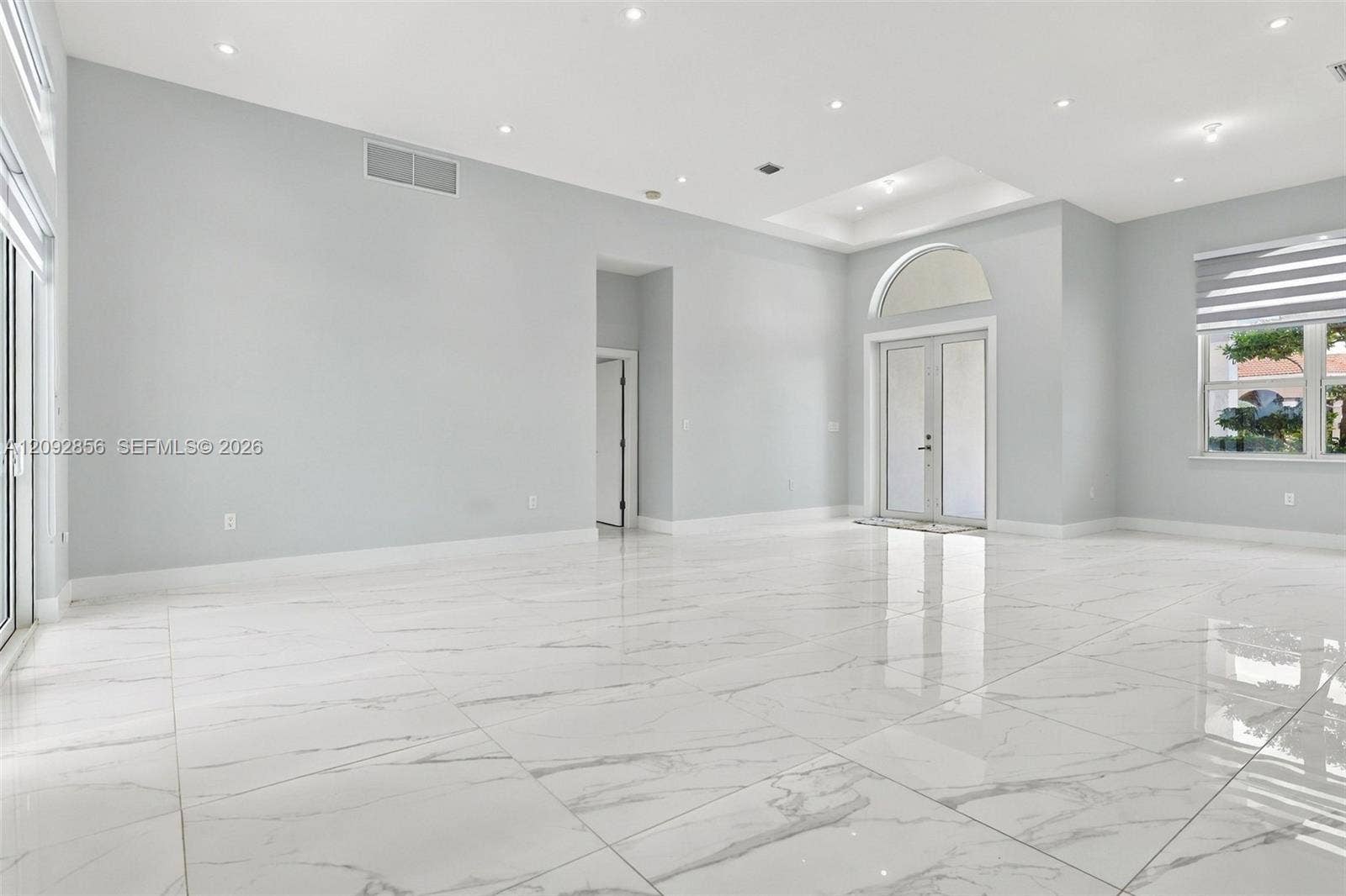 18919 SW 24th Street, #18919, Miramar, Miramar, FL 33029 High-ceiling interior featuring polished tile flooring, recessed lighting, double glass doors with an arched transom, and a tray ceiling