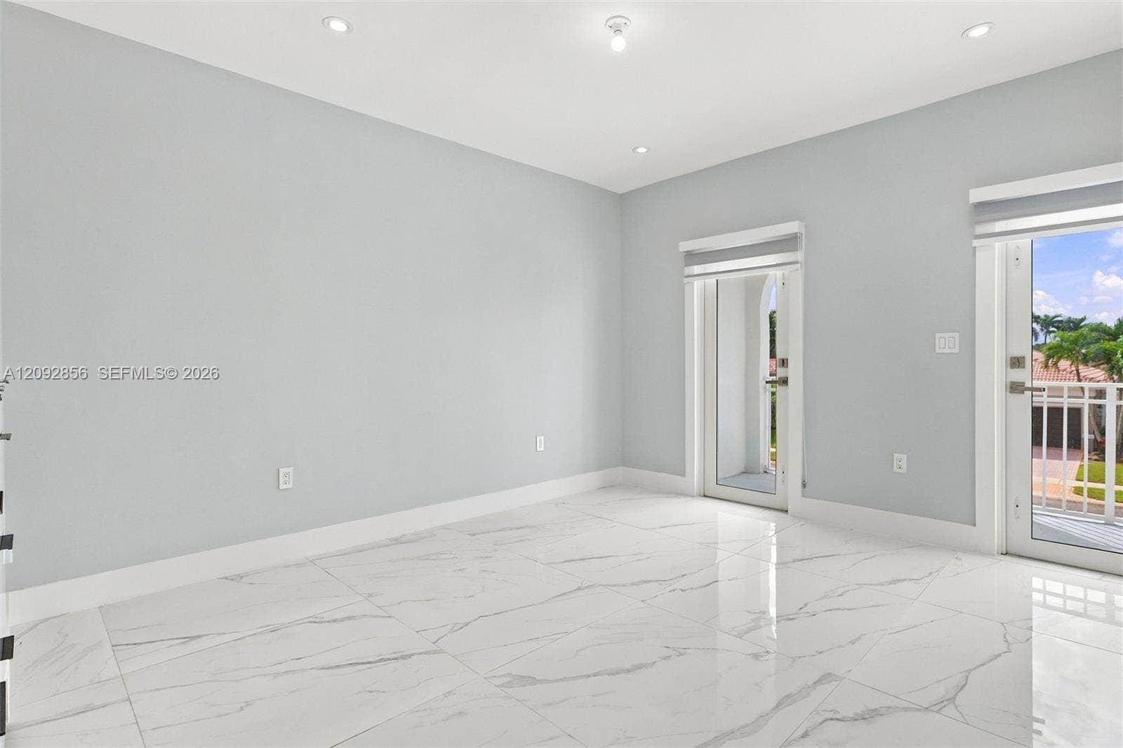 18919 SW 24th Street, #18919, Miramar, Miramar, FL 33029 5th bedroom (balcony) - 2nd floor - Neutral-toned interior featuring large-format stone-patterned tile flooring, recessed lighting, and dual glass-paneled exterior doors with integrated shades