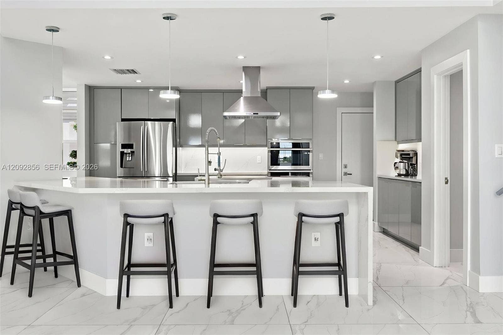 18919 SW 24th Street, #18919, Miramar, Miramar, FL 33029 Virtually staged - itchen featuring glossy grey cabinetry, stainless steel appliances, stone-surface waterfall island with a gooseneck faucet, pendant lighting, and large-format tile flooring