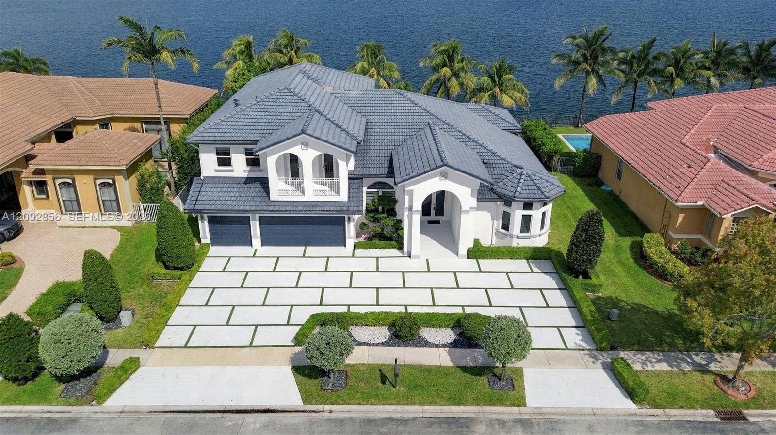 18919 SW 24th Street, #18919, Miramar, Miramar, FL 33029 Waterfront estate featuring a concrete tile roof, paver driveway with grass inlay, arched architectural detailing, and a three-car garage