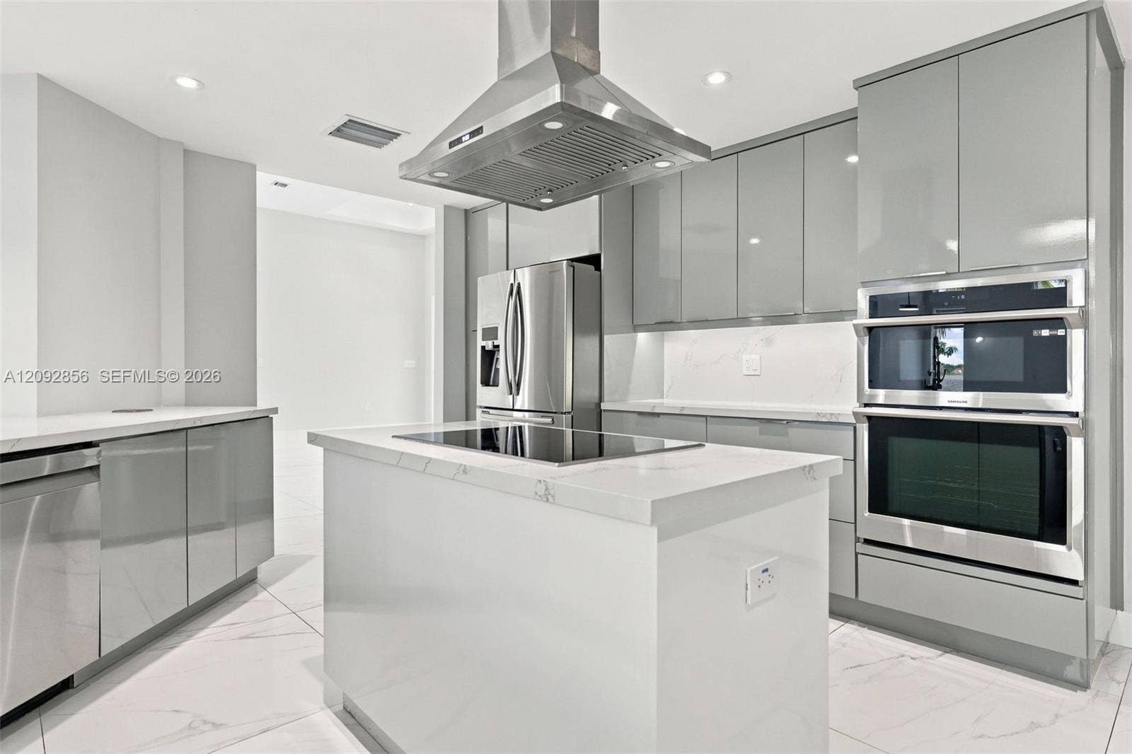 18919 SW 24th Street, #18919, Miramar, Miramar, FL 33029 Kitchen featuring high-gloss gray cabinetry, stone-finish countertops, stainless steel appliances, a center island with an integrated cooktop, and an overhead stainless steel range hood