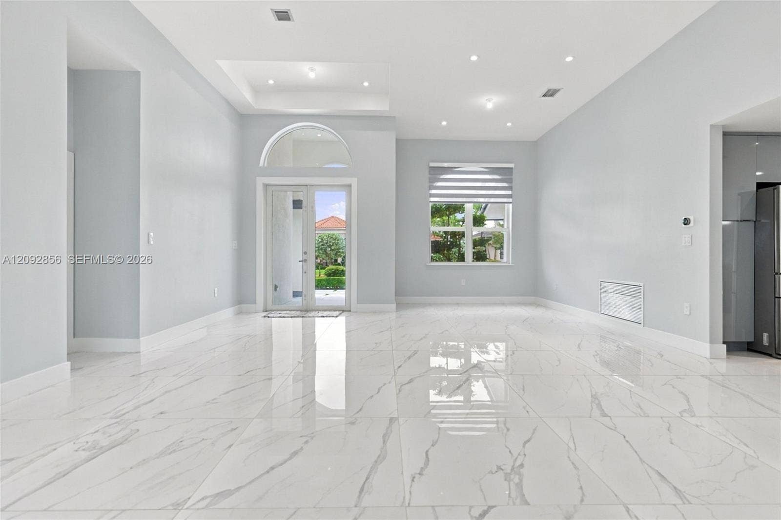 18919 SW 24th Street, #18919, Miramar, Miramar, FL 33029 Open-concept interior featuring large-format polished stone-finish flooring, recessed lighting, a tray ceiling, and a glass-paneled double door with an arched transom