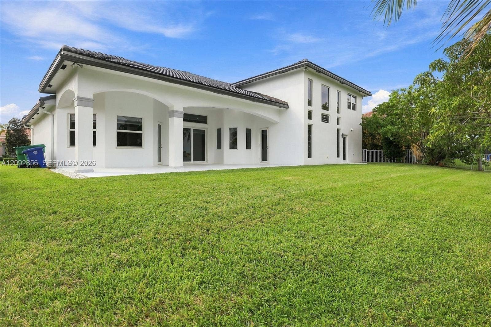 18919 SW 24th Street, #18919, Miramar, Miramar, FL 33029 Exterior featuring a multi-story stucco facade, a tile roof, an arched covered patio, and an expansive lawn