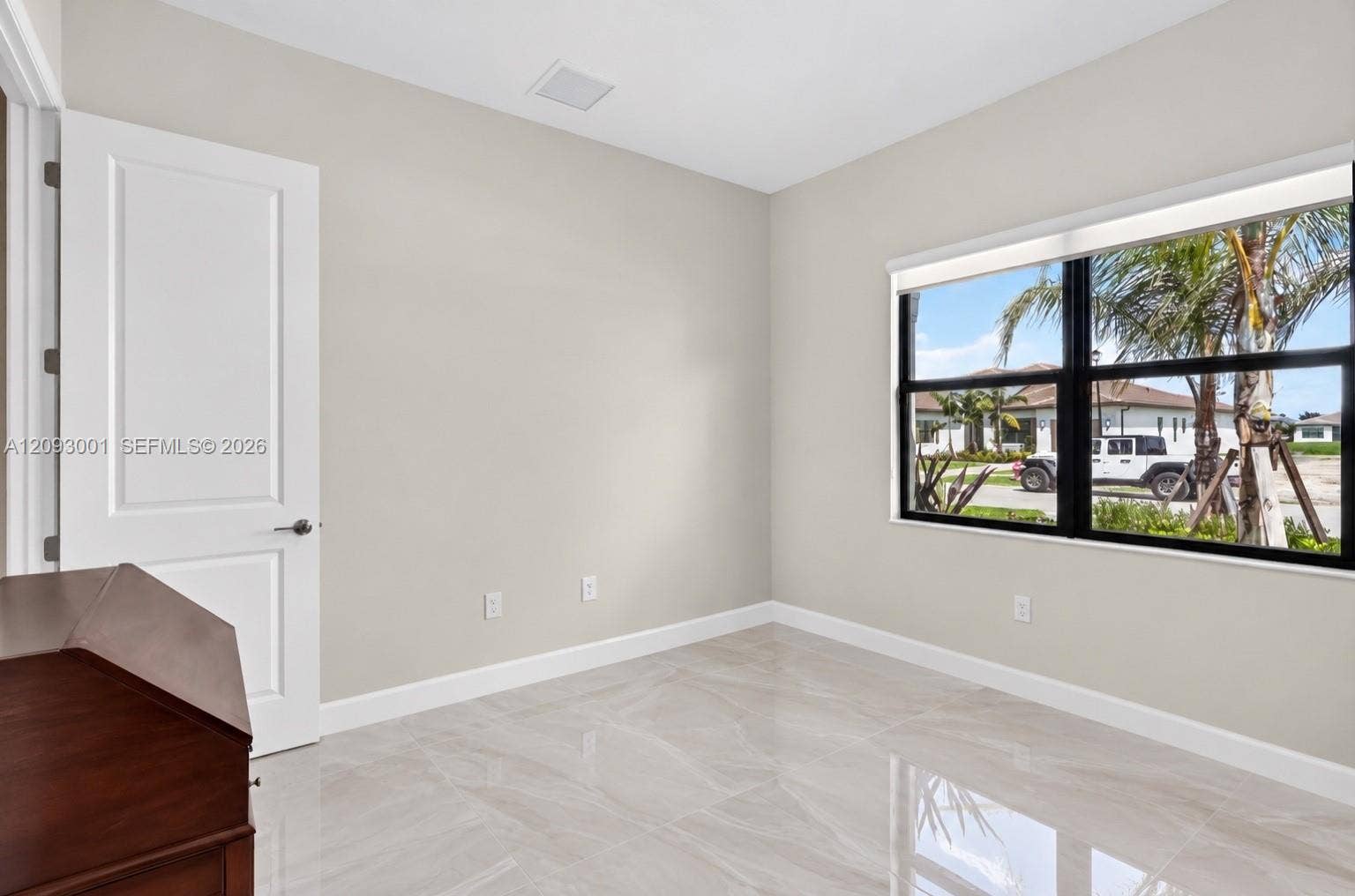 12688 SW Palmer Road, Port St Lucie, FL 34987 Neutral-toned walls, polished tile flooring, black-framed windows, and a solid-core paneled interior door