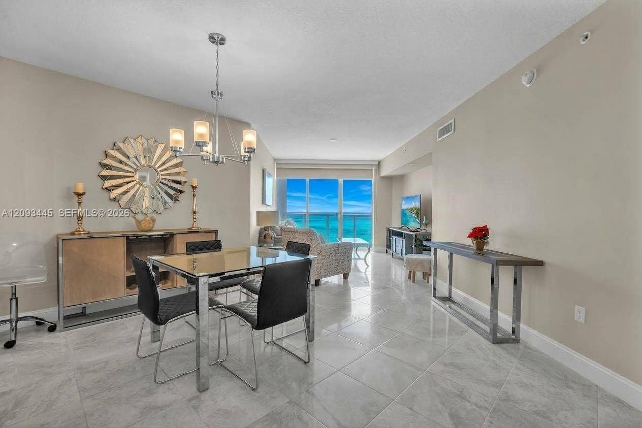 Spacious interior with tile flooring, a contemporary chandelier, and direct outdoor access through glass doors