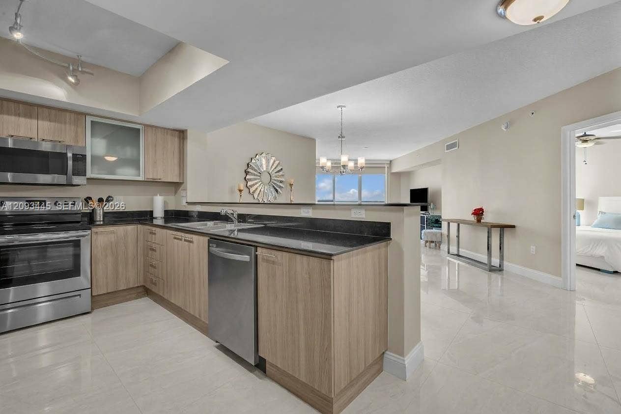 Kitchen cabinets modernized by A.I Kitchen featuring stainless steel appliances, wood-finish cabinetry, dark countertops, and tile flooring