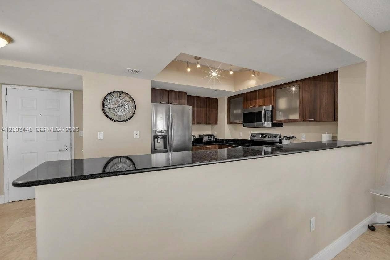 Kitchen cabinets modernized by A.I Kitchen featuring dark wood-finish cabinetry, black countertops, stainless steel appliances, and recessed lighting