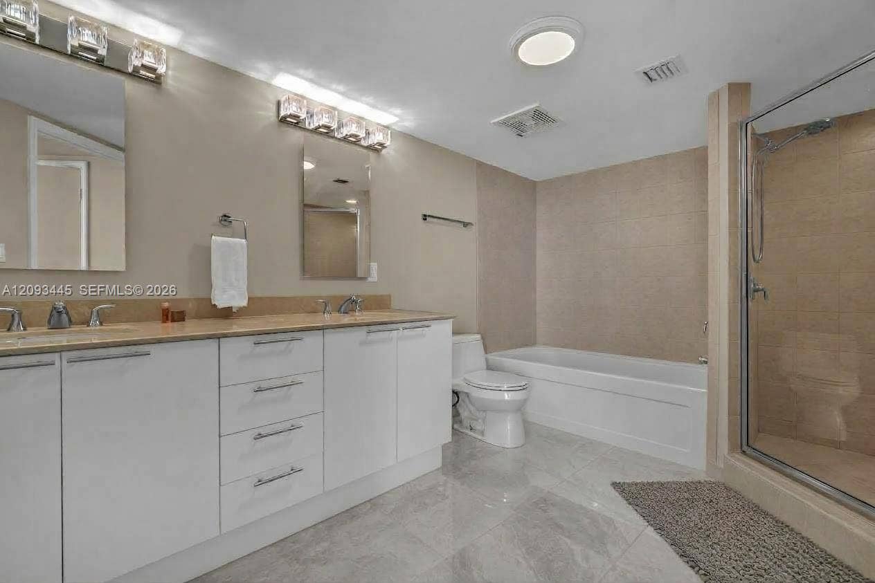 Spa-inspired primary bathroom featuring a dual-sink vanity with ample storage, wood-finish countertops, and polished nickel fixtures