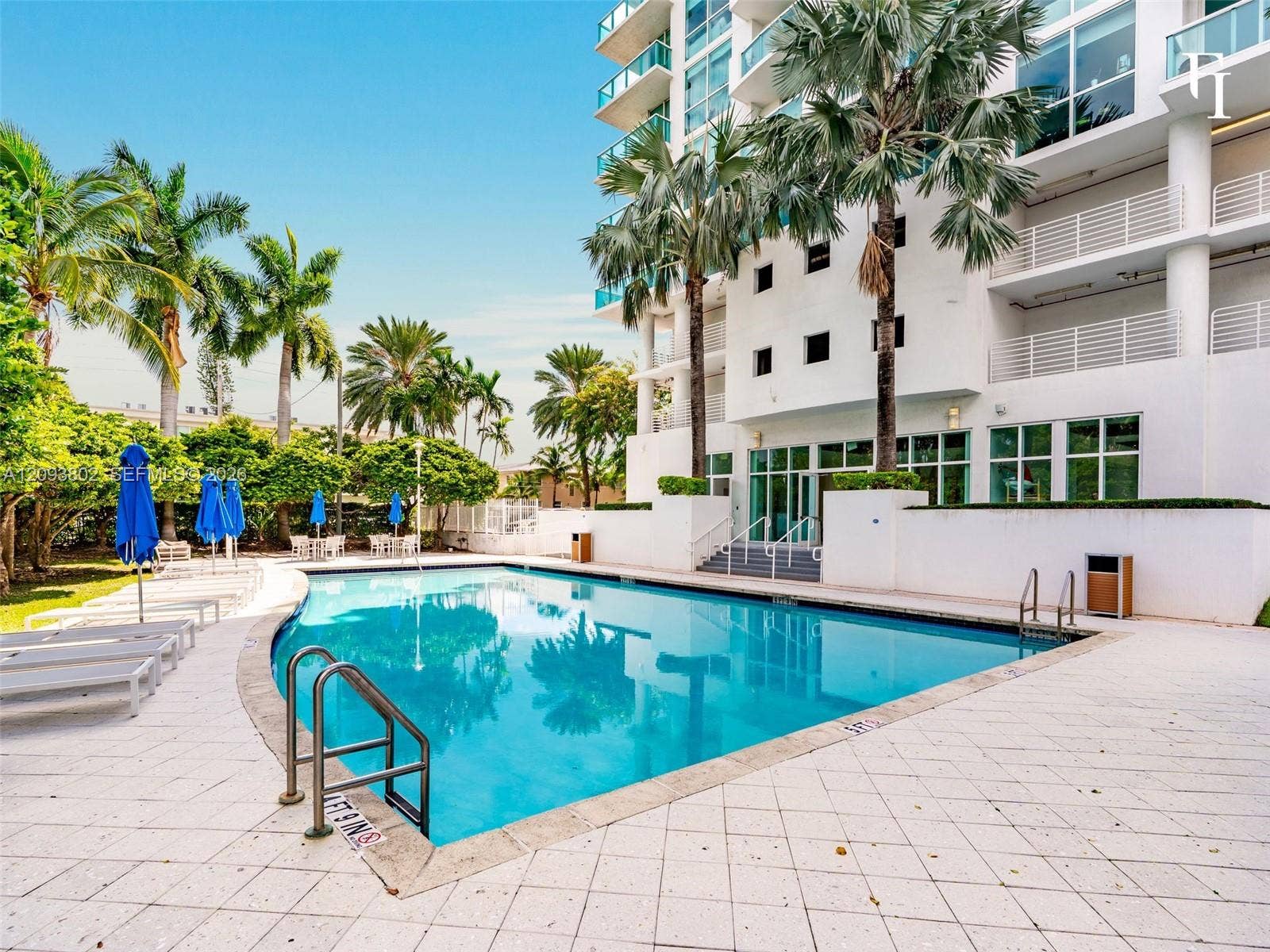 7910 Harbor Island Drive, #909, North Bay Village, North Bay Village, FL 33141 In-ground swimming pool with metal ladder entry, expansive stone paver deck, and surrounding mature palm trees
