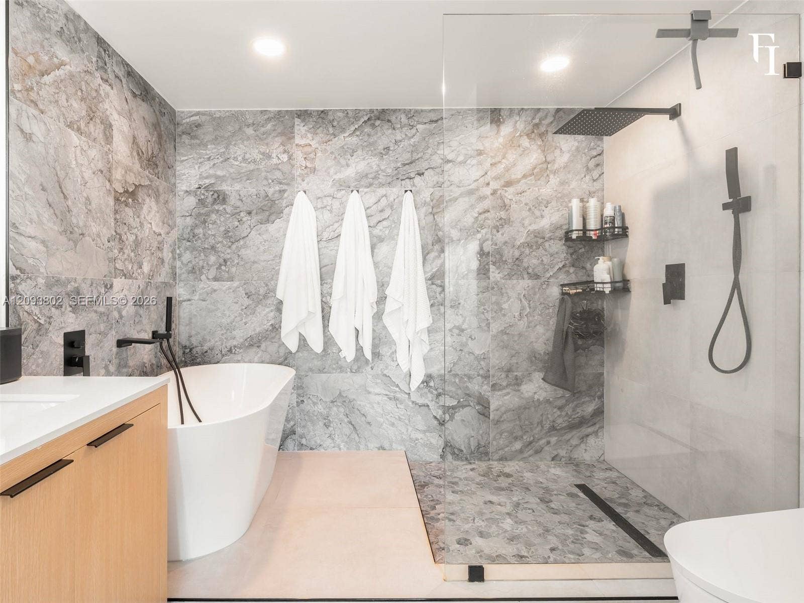7910 Harbor Island Drive, #909, North Bay Village, North Bay Village, FL 33141 Freestanding soaking tub with matte black wall-mounted faucet, walk-in shower featuring a glass enclosure and rainfall showerhead, and large-format stone-finish tile wall accents
