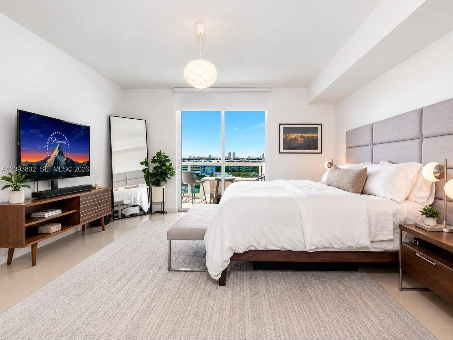 7910 Harbor Island Drive, #909, North Bay Village, North Bay Village, FL 33141 Floor-to-ceiling glass sliding doors opening to a balcony, neutral tile flooring, and a bespoke upholstered headboard