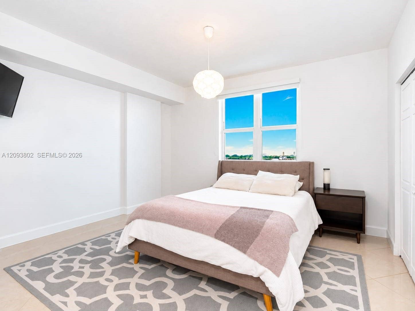 7910 Harbor Island Drive, #909, North Bay Village, North Bay Village, FL 33141 Neutral-toned interior space featuring light-colored tile flooring, bright white walls, large multi-pane window, and a modern globe pendant light fixture
