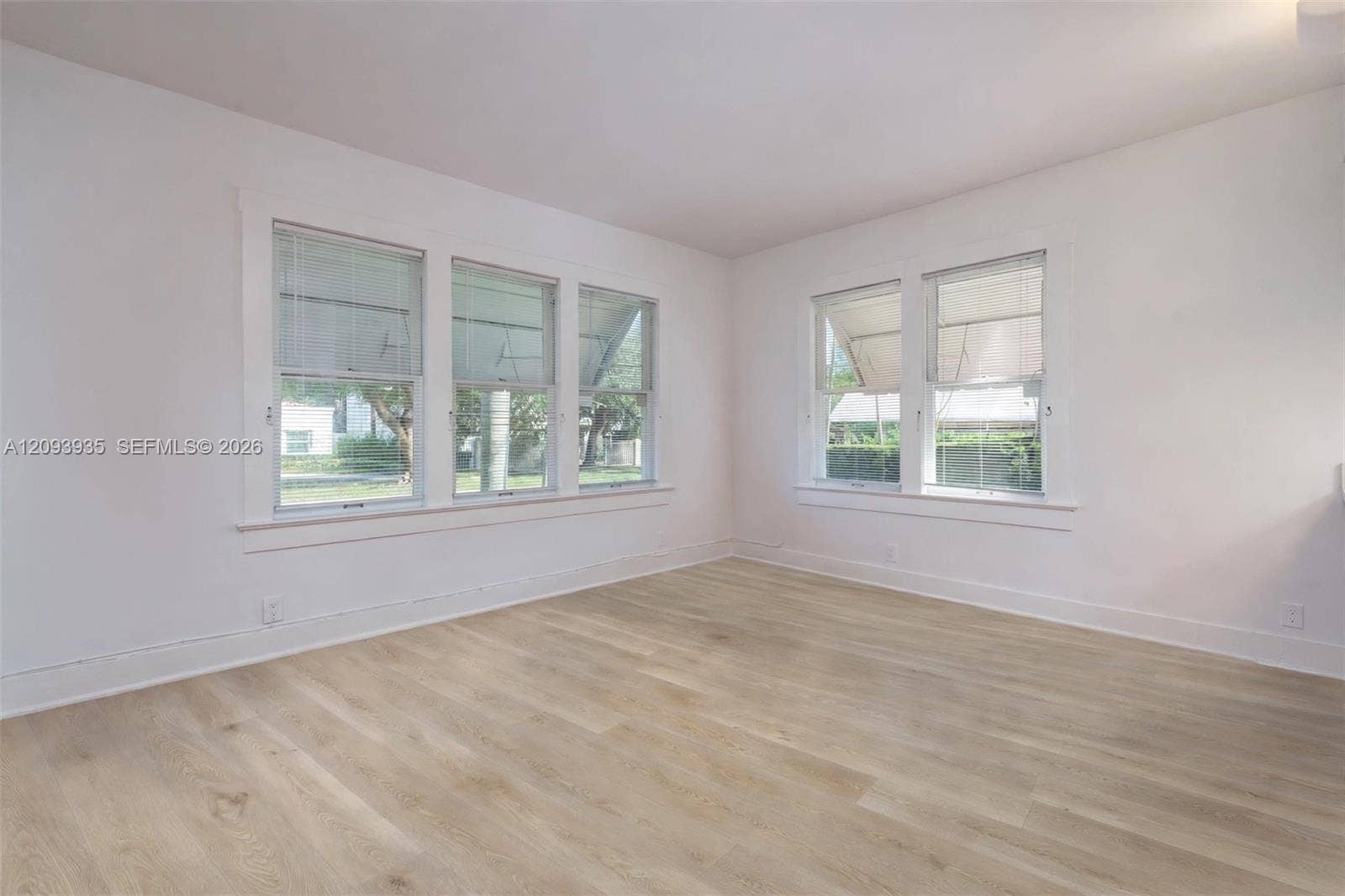 Interior space featuring wood-finish flooring, white walls, and multiple double-hung windows with white casing