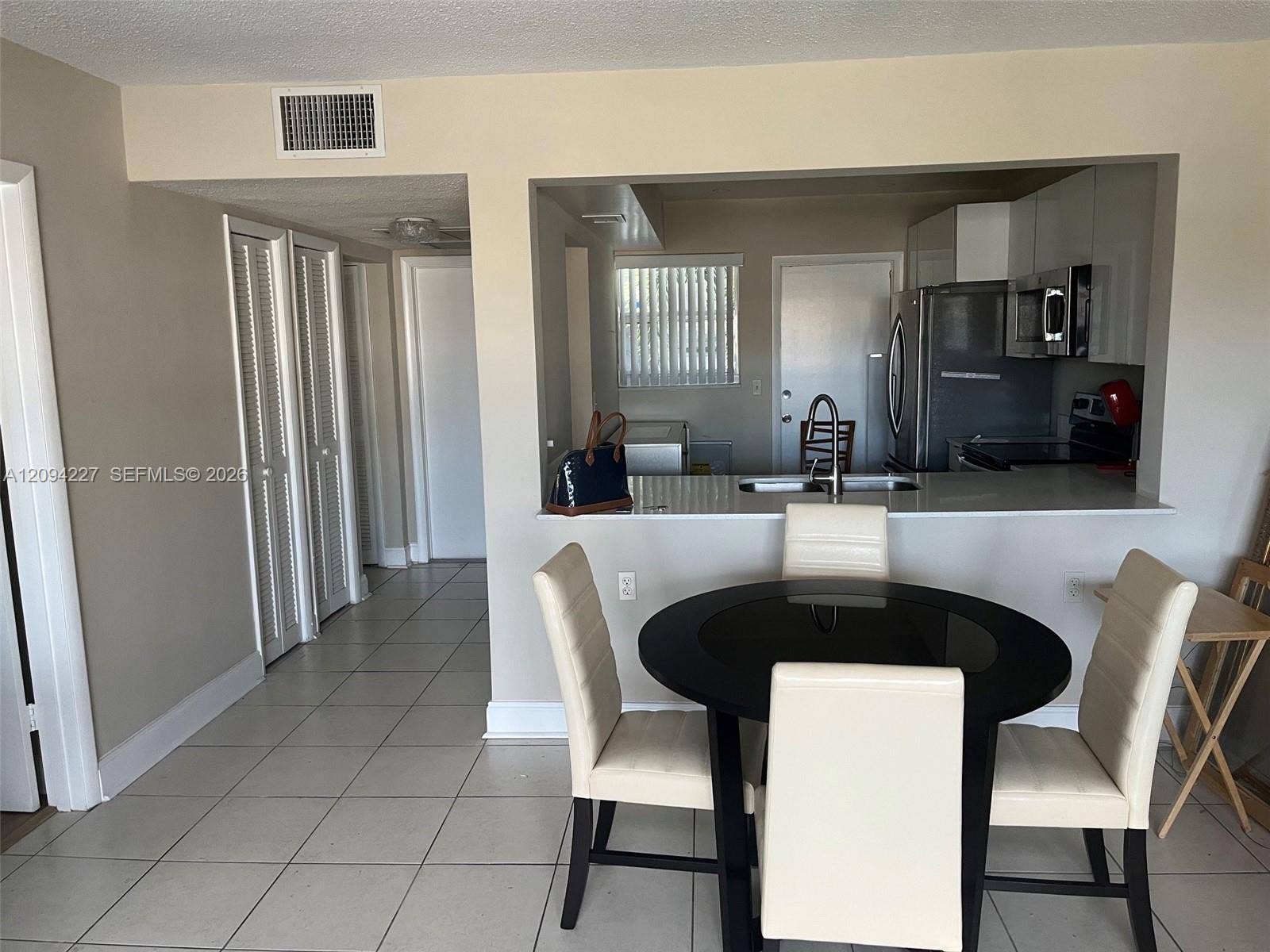 Kitchen featuring a stone-look countertop, stainless steel refrigerator, built-in microwave, and tile flooring throughout