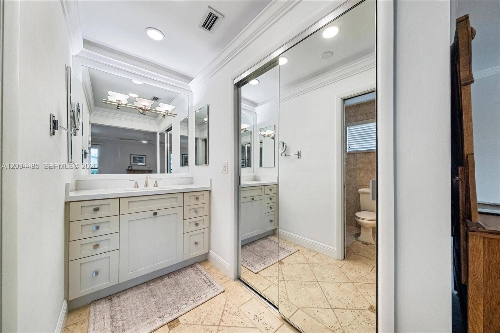 Vanity featuring a stone-surface countertop, integrated undermount sink, multi-drawer cabinetry, and a large wall-mounted mirror