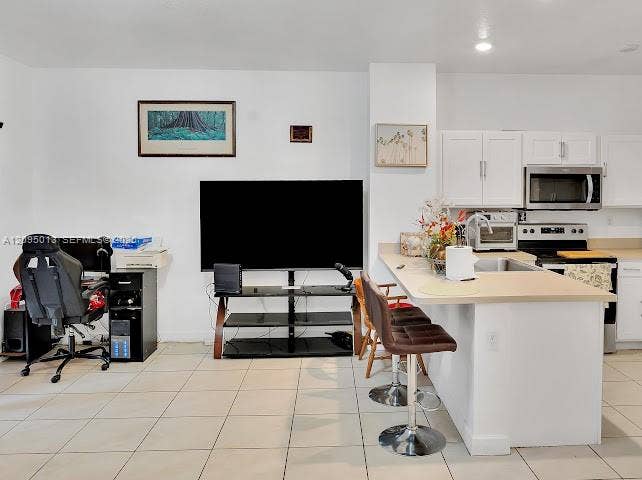 Kitchen featuring white cabinetry, solid-surface countertops, recessed lighting, and tile flooring