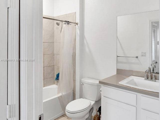 Bathroom featuring a white vanity cabinet, solid-surface countertop with an integrated basin, large wall-mounted mirror, and a tub-shower combination with light-toned wall tile