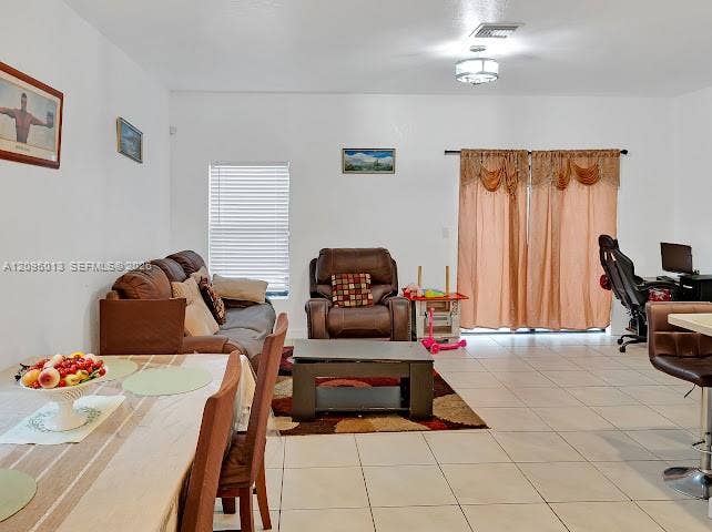 Open living area featuring neutral tile flooring, recessed lighting, and large sliding glass doors
