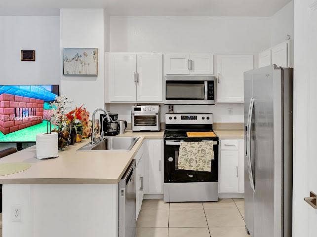 Kitchen featuring white cabinetry, stainless steel appliances, solid-surface countertops, and tile flooring