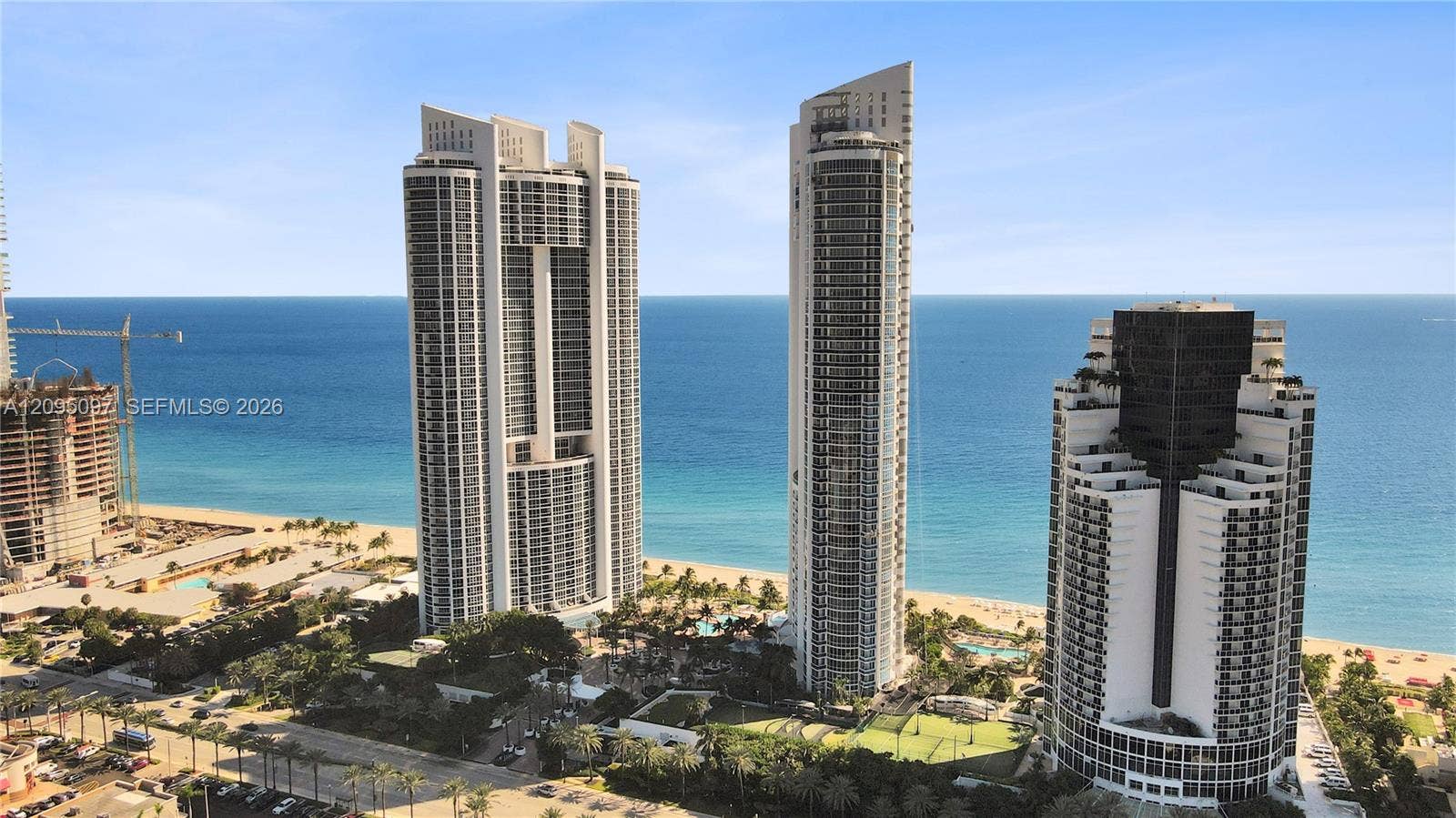 18201 Collins Avenue, #1407, Sunny Isles Beach, FL 33160 High-rise residential architecture featuring floor-to-ceiling glass, extensive wrap-around balconies, direct oceanfront positioning, and coastal shoreline access