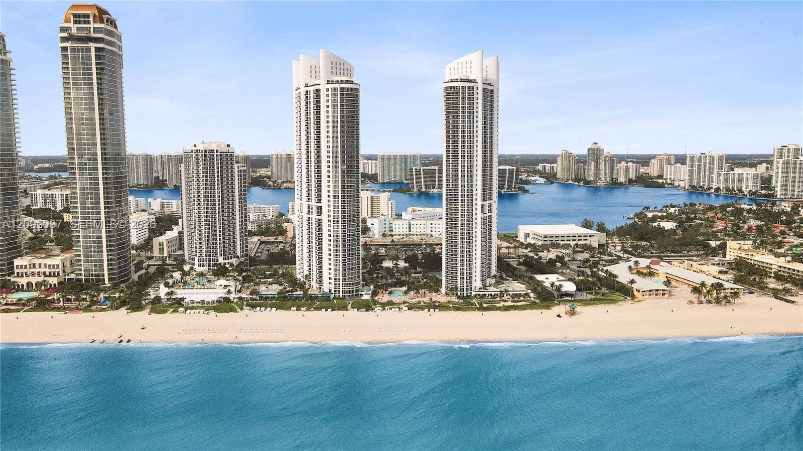 18201 Collins Avenue, #1407, Sunny Isles Beach, FL 33160 High-rise residential towers featuring glass-facade architecture, direct sandy shoreline access, and proximity to expansive waterfront scenery