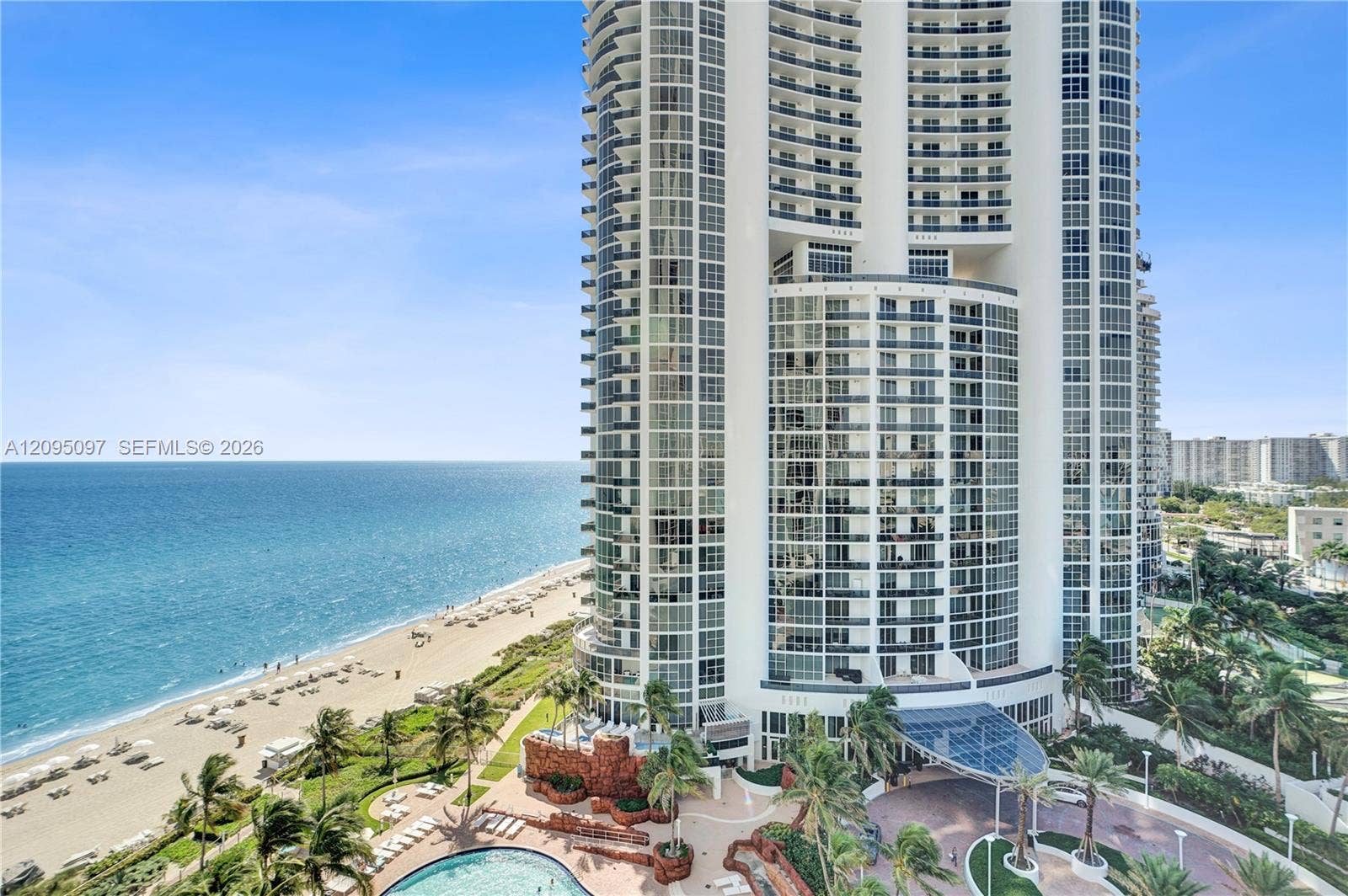 18201 Collins Avenue, #1407, Sunny Isles Beach, FL 33160 High-rise residential tower featuring floor-to-ceiling glass windows, wraparound balconies, an oceanfront location, a resort-style swimming pool, and a porte-cochre entry