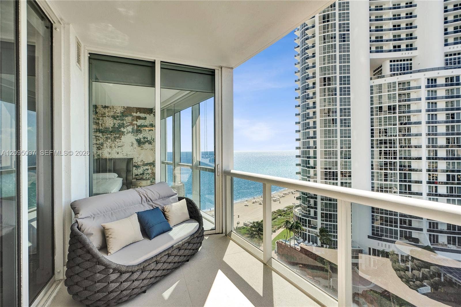 18201 Collins Avenue, #1407, Sunny Isles Beach, FL 33160 Covered private balcony featuring glass panel railings, floor-to-ceiling sliding glass doors, and panoramic ocean and coastline exposure