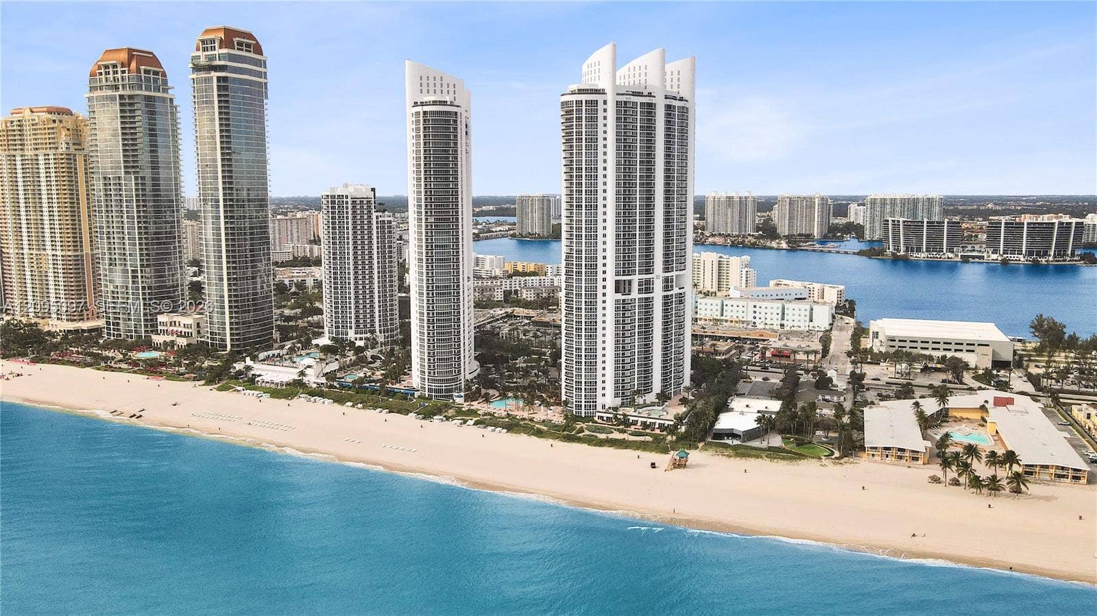 18201 Collins Avenue, #1407, Sunny Isles Beach, FL 33160 High-rise coastal towers featuring direct oceanfront access, private sandy beach frontage, and panoramic water horizons