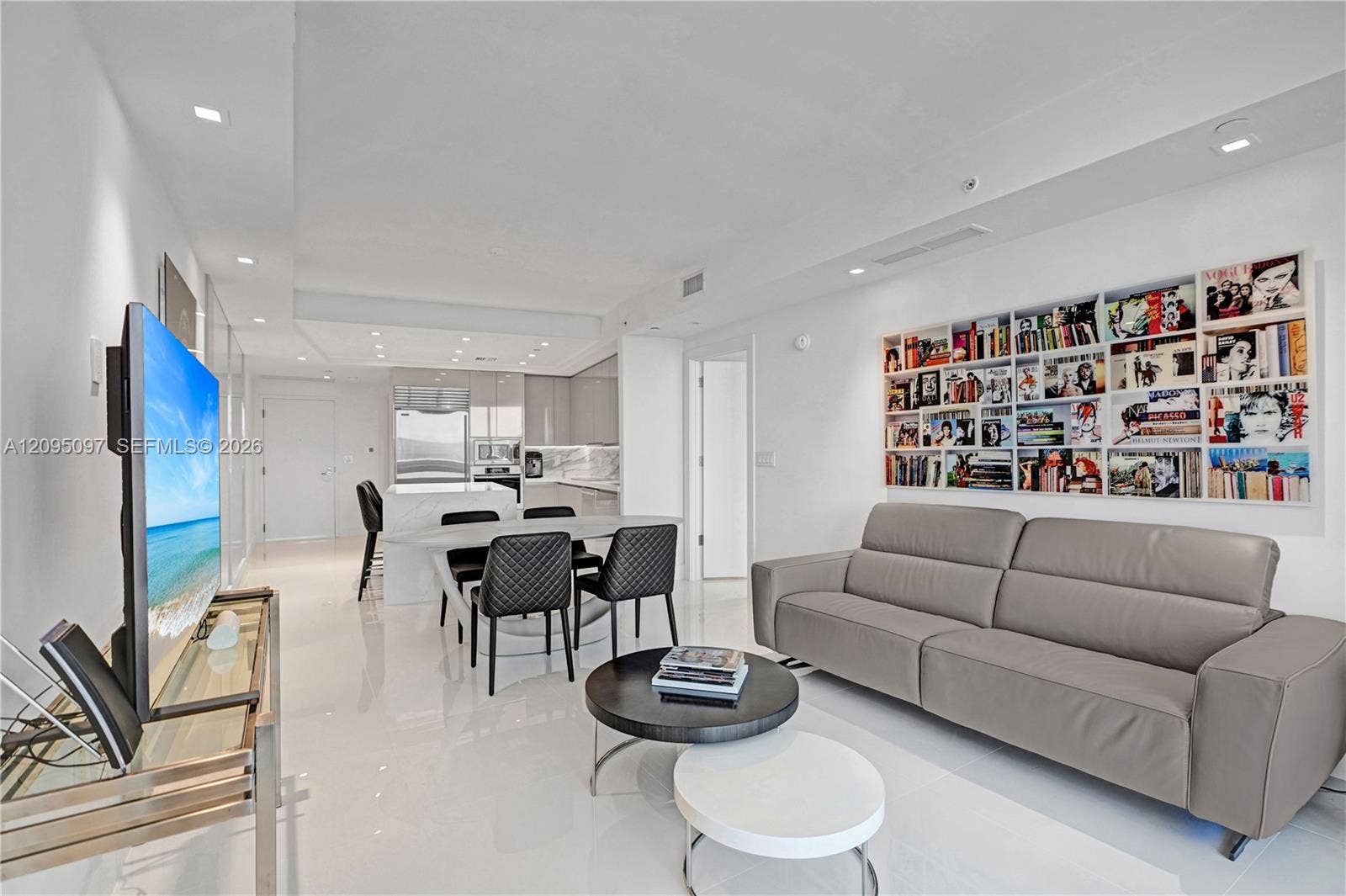 18201 Collins Avenue, #1407, Sunny Isles Beach, FL 33160 Open-concept interior featuring high-gloss flooring, recessed lighting, a built-in recessed shelving unit, and a kitchen equipped with stone-surfaced countertops and stainless steel appliances