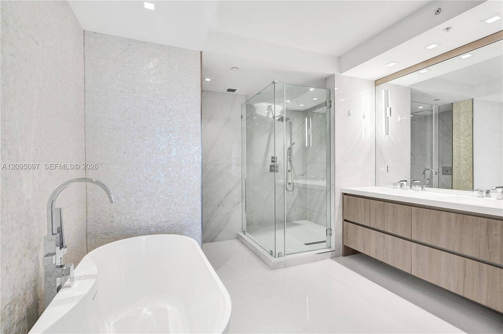18201 Collins Avenue, #1407, Sunny Isles Beach, FL 33160 Freestanding soaking tub with floor-mounted faucet, glass-enclosed shower, wall-to-wall vanity with double sinks, and recessed lighting