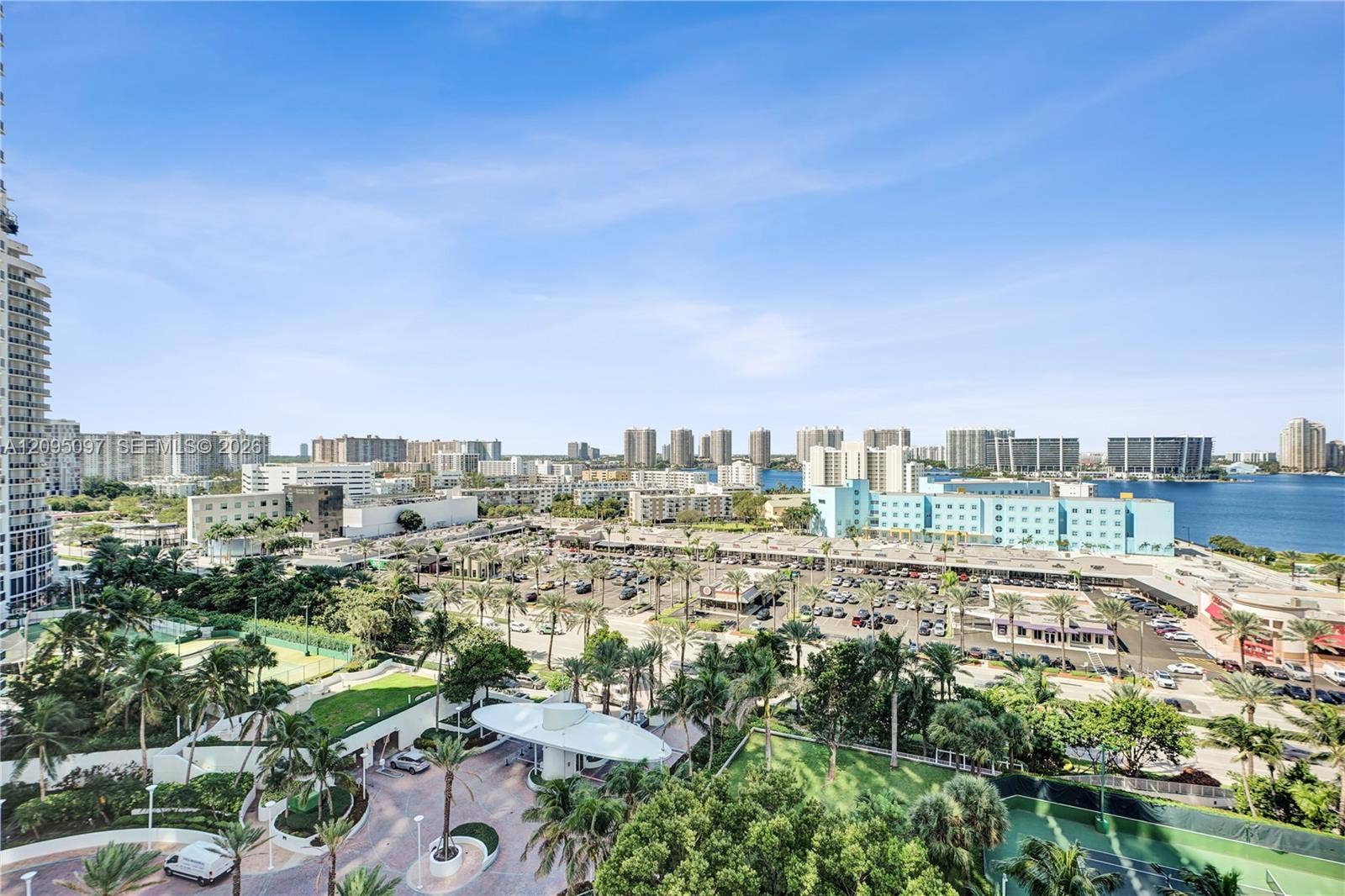 18201 Collins Avenue, #1407, Sunny Isles Beach, FL 33160 Elevated exterior perspective featuring a circular porte-cochre, paved motor court, mature landscaping, and tennis courts