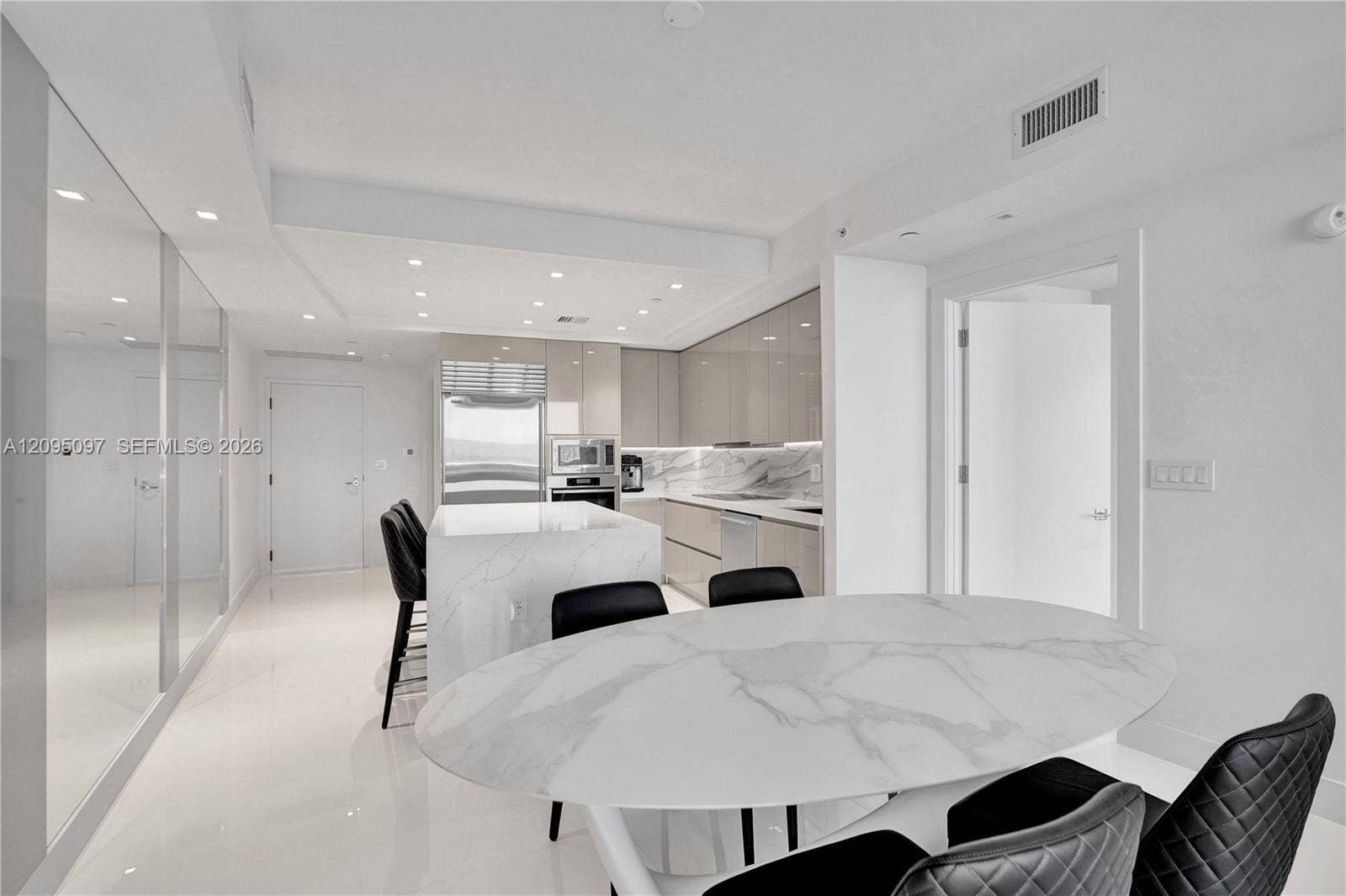 18201 Collins Avenue, #1407, Sunny Isles Beach, FL 33160 Contemporary kitchen featuring high-gloss cabinetry, stone-surface island, integrated stainless steel appliances, recessed lighting, and polished stone-finish flooring