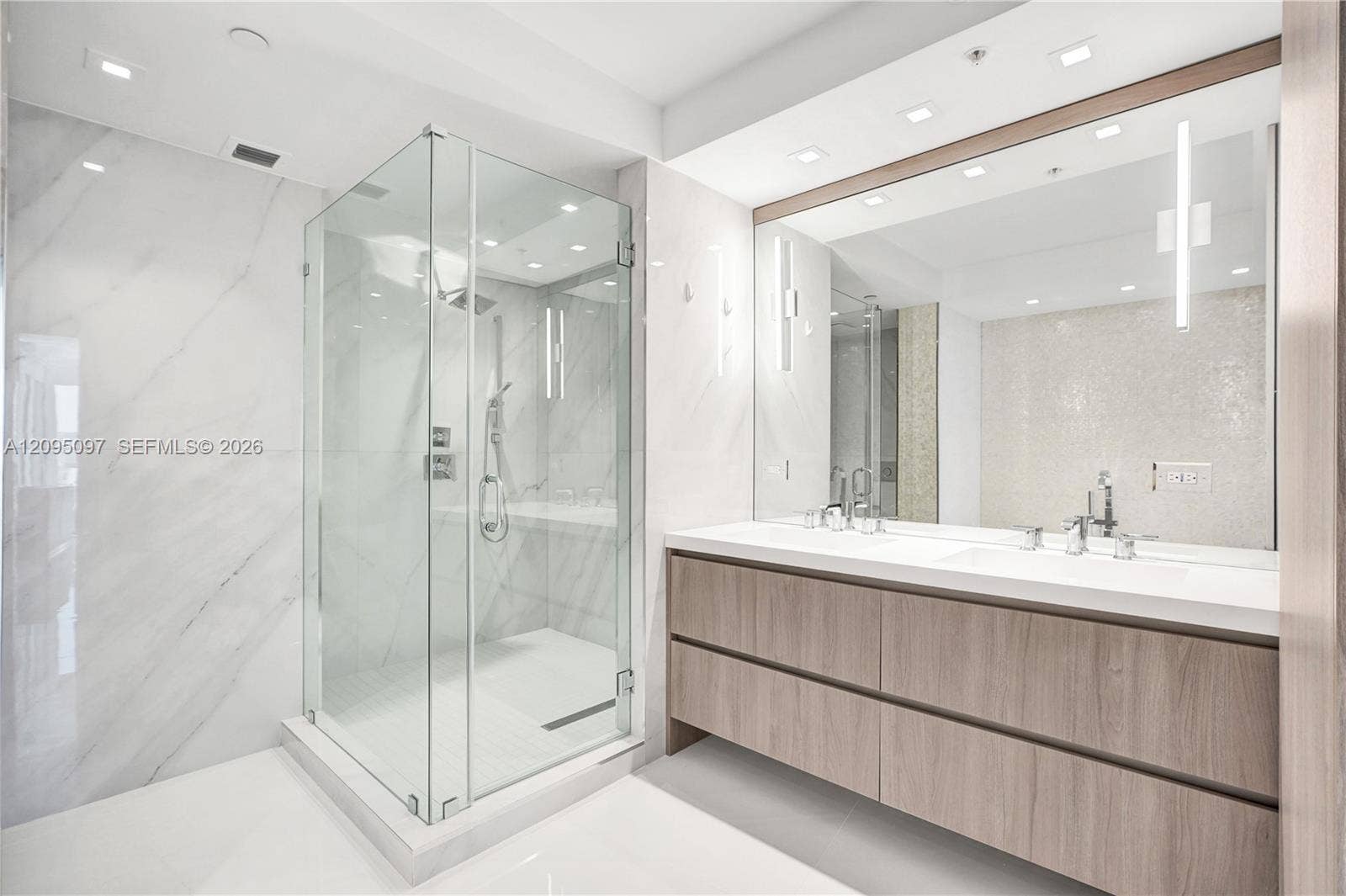 18201 Collins Avenue, #1407, Sunny Isles Beach, FL 33160 Floating vanity with dual rectangular sinks, frameless glass-enclosed shower, large-format wall tiling, recessed lighting, and integrated wall mirror
