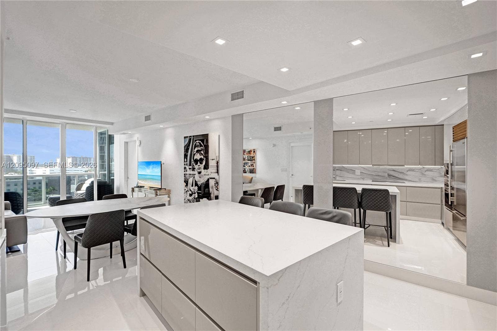 18201 Collins Avenue, #1407, Sunny Isles Beach, FL 33160 Open-concept interior featuring high-gloss cabinetry, a central island with a solid surface countertop, stone-finish backsplash, recessed ceiling lighting, and floor-to-ceiling windows
