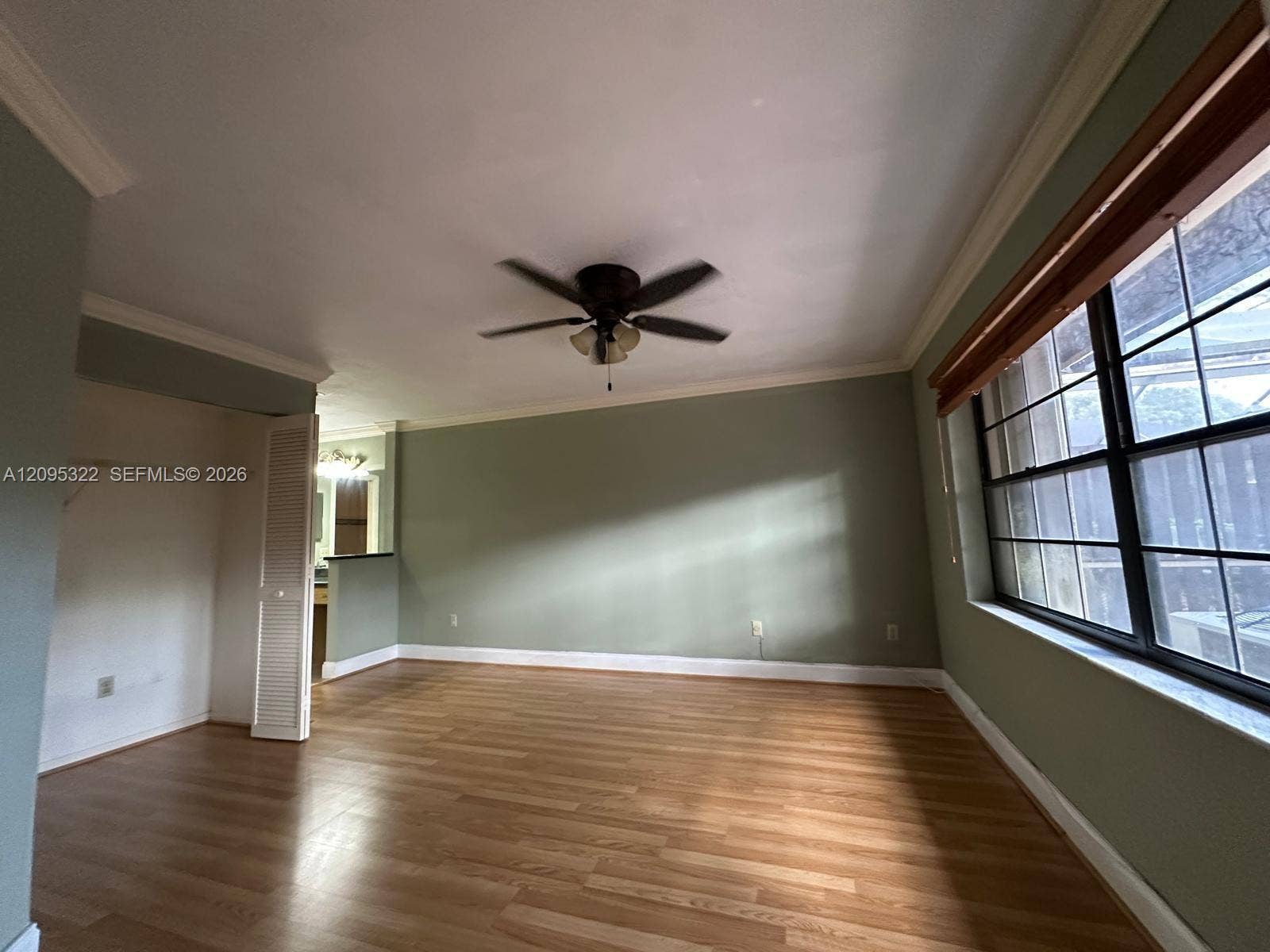 10061 SW 137th Place, Miami, FL 33186 Room featuring wood-finish flooring, crown molding, a ceiling fan with integrated lighting, and multi-pane windows with wood-trim framing