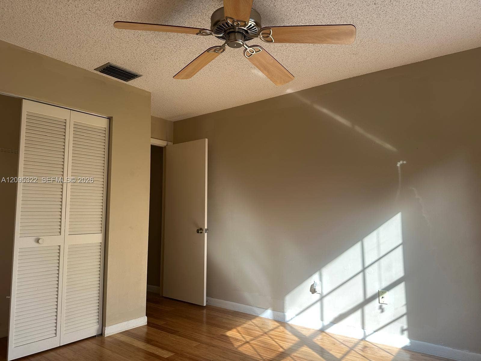 10061 SW 137th Place, Miami, FL 33186 Wood-finish flooring, ceiling fan with wood-toned blades, and louvered double-door closet