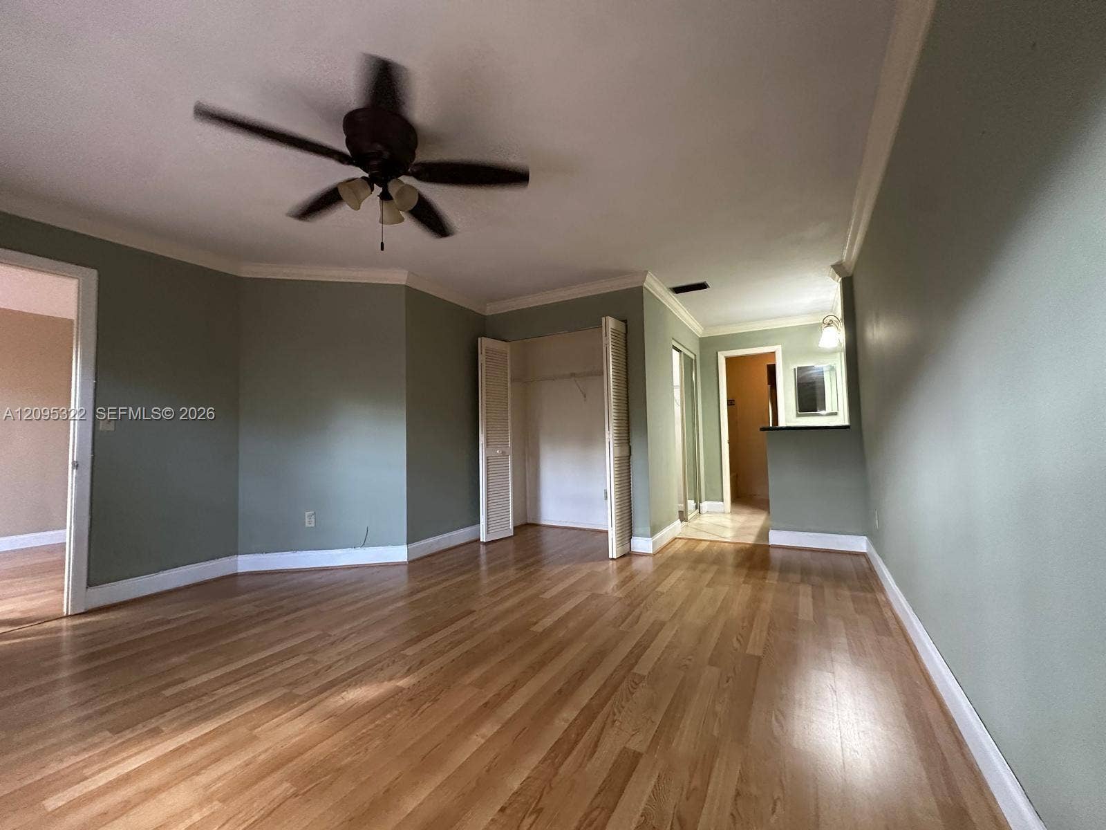10061 SW 137th Place, Miami, FL 33186 Interior space featuring wood-finish flooring, crown molding, a ceiling fan with integrated lighting, and a closet with bifold doors