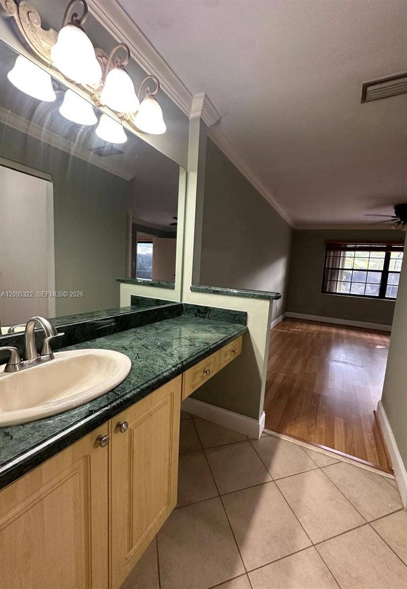 10061 SW 137th Place, Miami, FL 33186 Vanity featuring stone-surfaced countertop, integrated oval basin, light-finish cabinetry, and crown molding