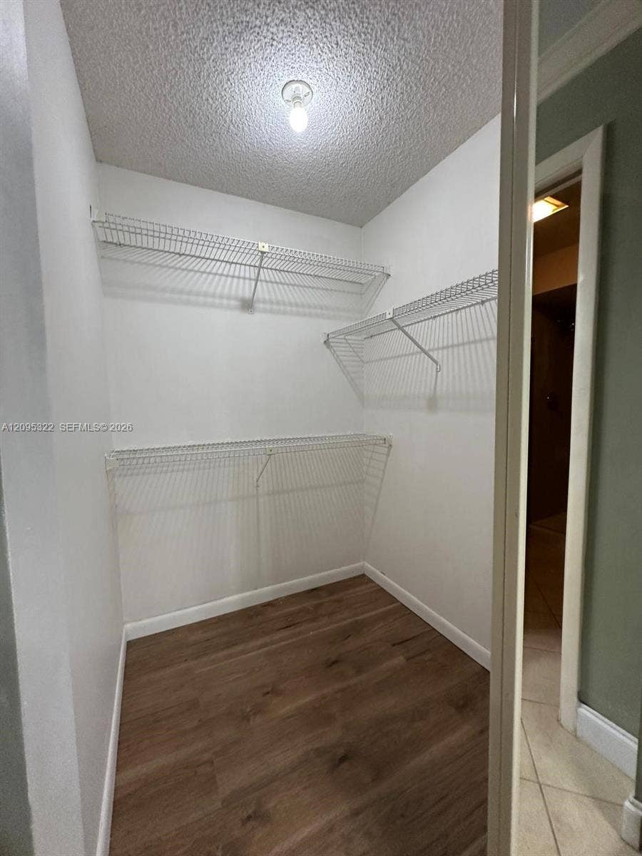 10061 SW 137th Place, Miami, FL 33186 Storage closet featuring wood-finish flooring, white walls, and tiered metal wire shelving