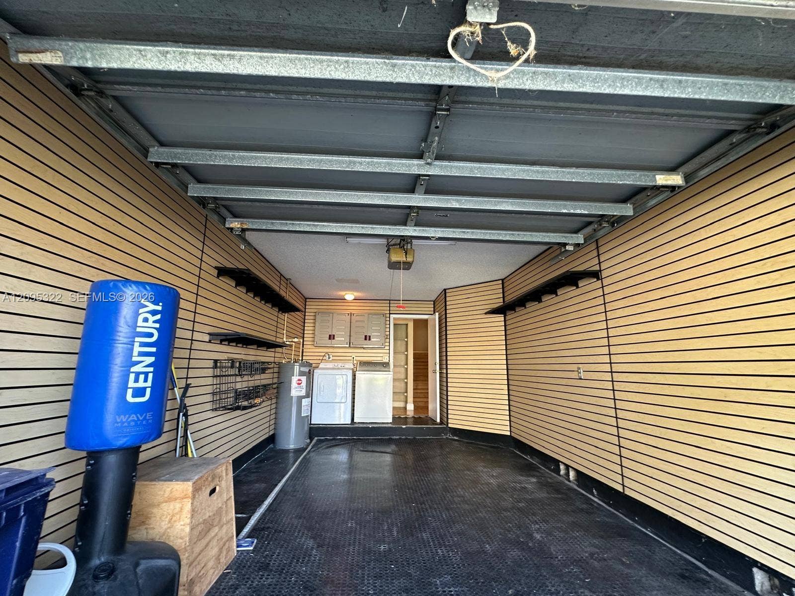 10061 SW 137th Place, Miami, FL 33186 Garage interior featuring horizontal slat-wall paneling, rubberized textured flooring, integrated wall-mounted shelving, and laundry hookups