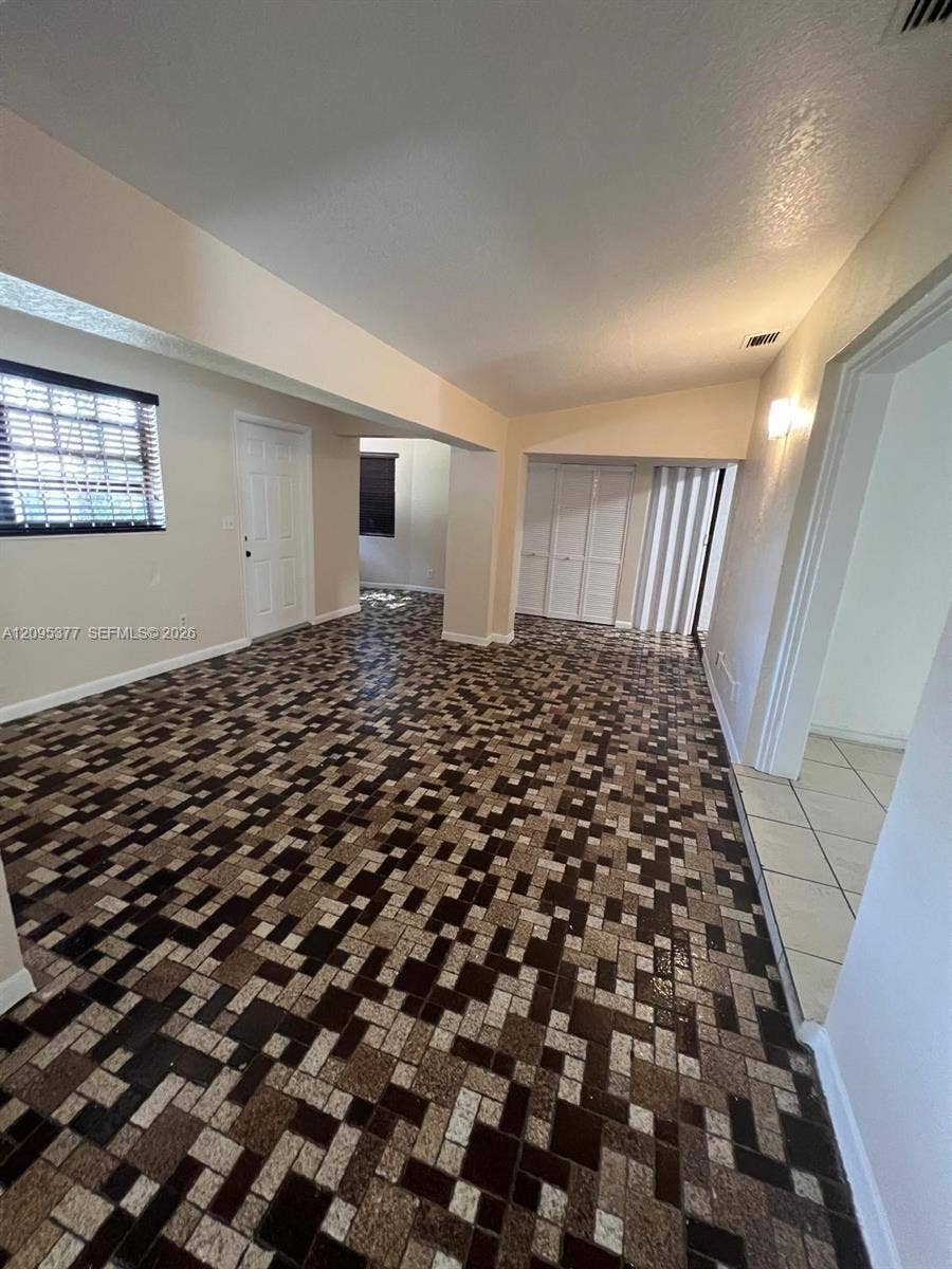 570 NW 41st Street, Miami, FL 33127 Interior space featuring geometric mosaic-tile flooring, vaulted ceilings, and built-in closet storage with bi-fold doors