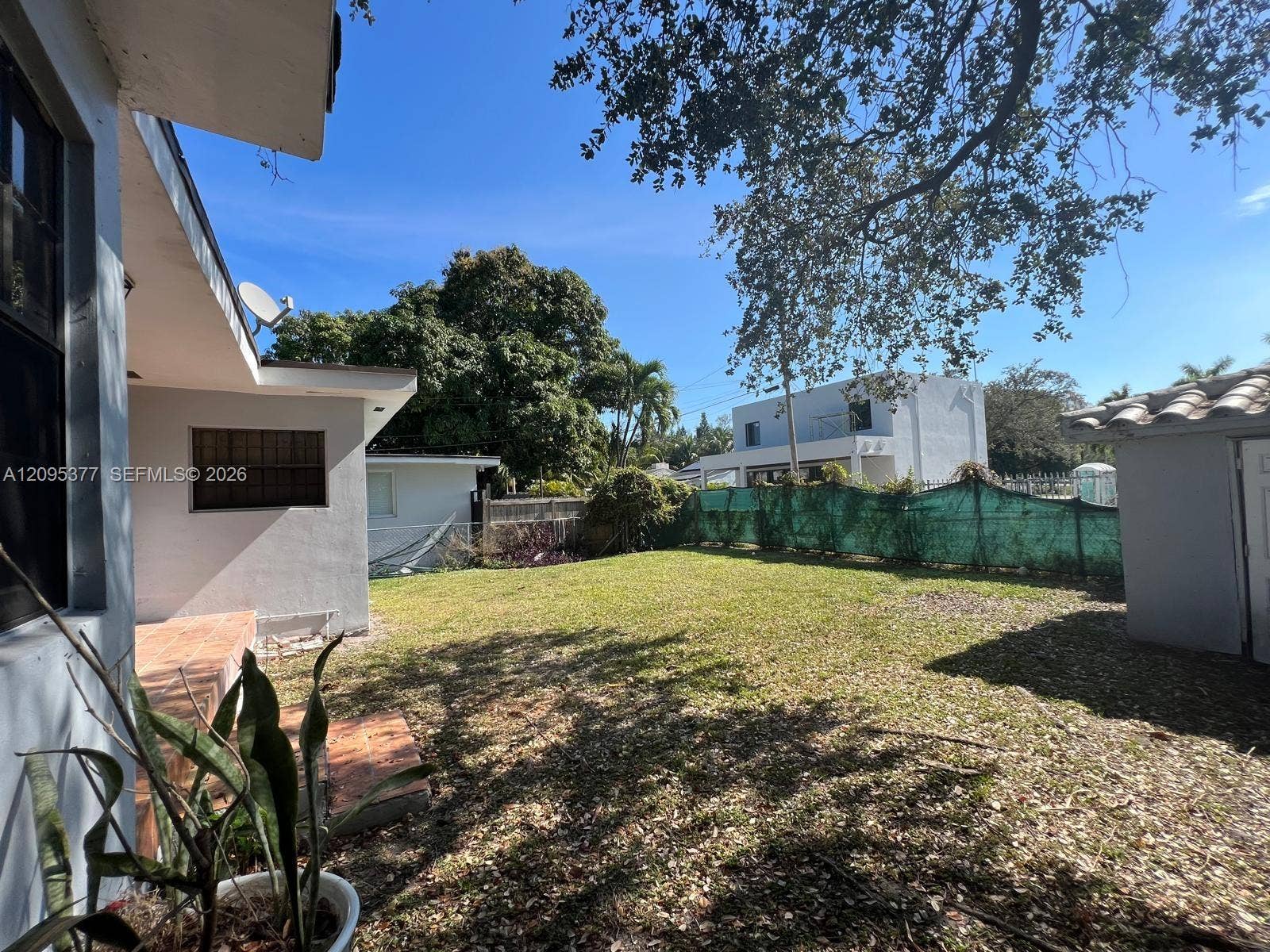 570 NW 41st Street, Miami, FL 33127 Backyard featuring a grass lawn, paved patio, detached storage structure, and perimeter fencing