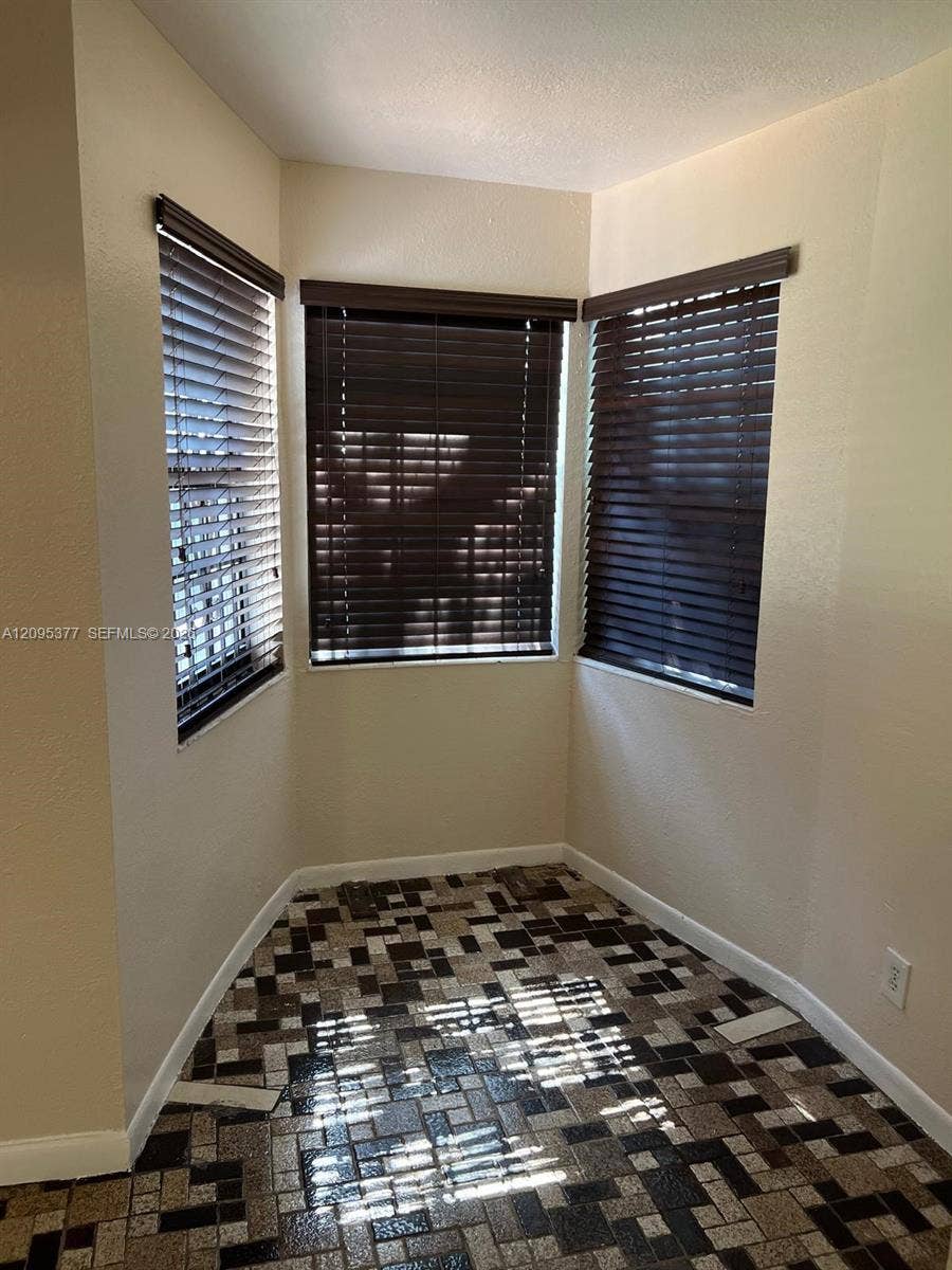 570 NW 41st Street, Miami, FL 33127 Bay window featuring three operable windows with dark-finish horizontal blinds and mosaic tile flooring