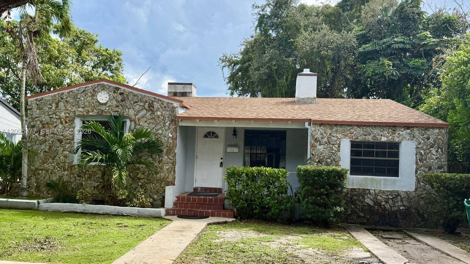 570 NW 41st Street, Miami, FL 33127 Exterior facade featuring natural stone masonry, shingled roofing, a covered front entryway, and brick porch stairs