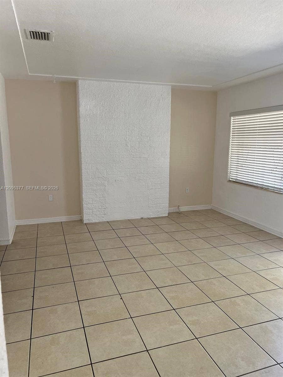 570 NW 41st Street, Miami, FL 33127 Interior space featuring large-format neutral tile flooring and a painted brick chimney breast